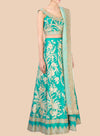 Teal embroidered traditional outfit with gold details on a beige background