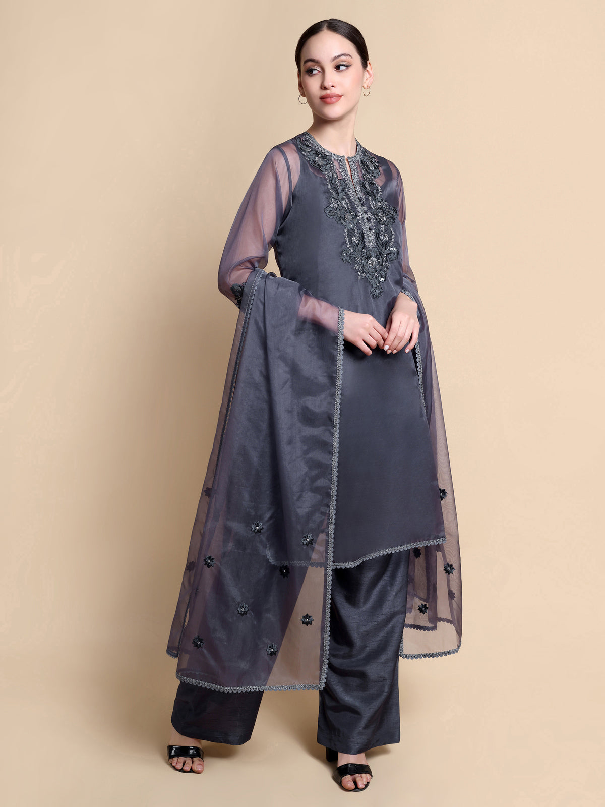 Woman wearing a gray traditional outfit with a long jacket on a beige background