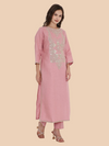 Woman wearing a pink kurta with intricate embroidery on a beige background