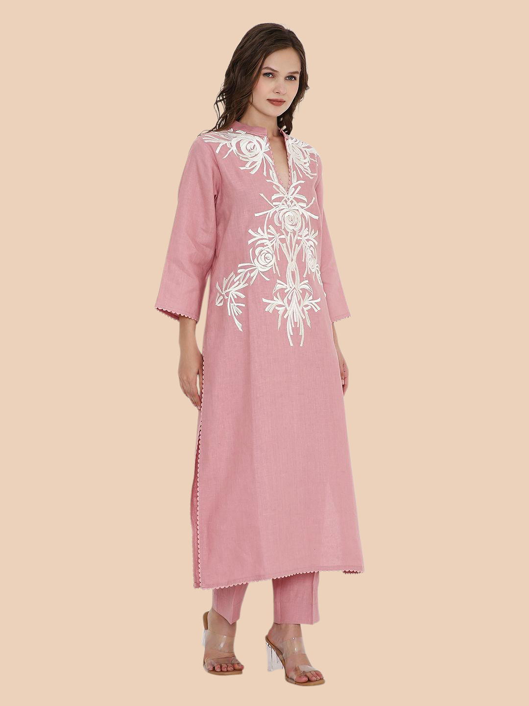 Woman wearing a pink kurta with white embroidery on a beige background