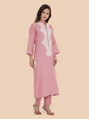 Woman wearing a pink kurta with white embroidery on a beige background