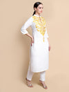 Woman wearing a white kurta with gold embroidery on a beige background
