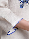 Close-up of a garment with blue embroidery on a beige background