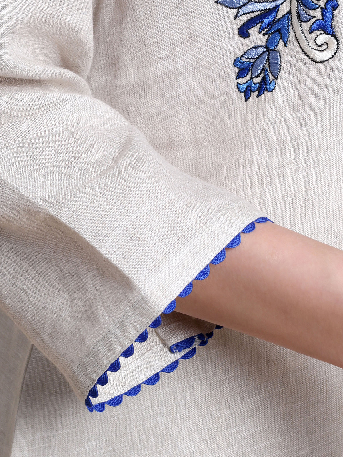 Close-up of a garment with blue embroidery on a beige background