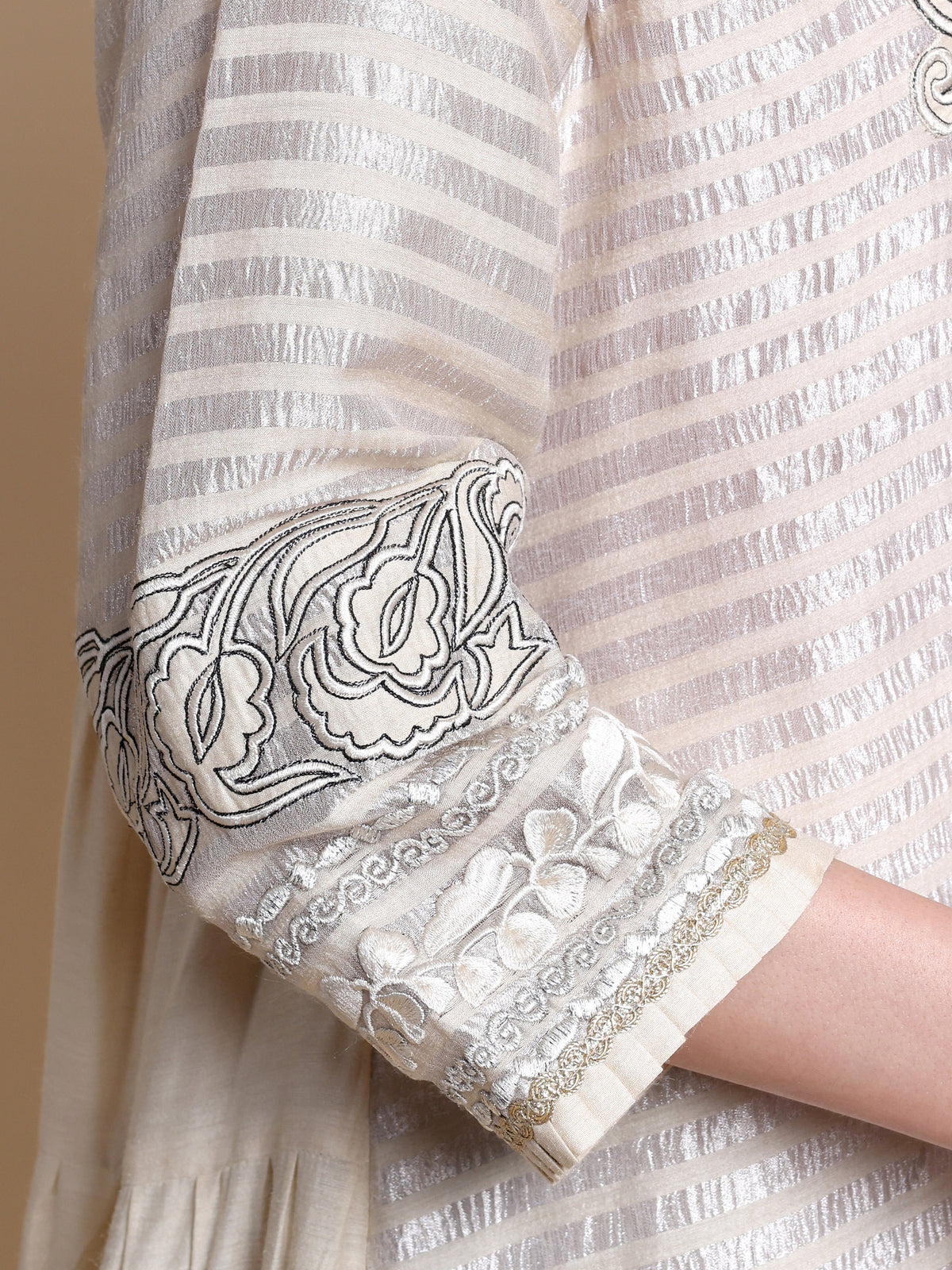 Close-up of a white garment with black floral embroidery on a beige background