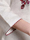 Close-up of a garment with red floral embroidery on a beige background