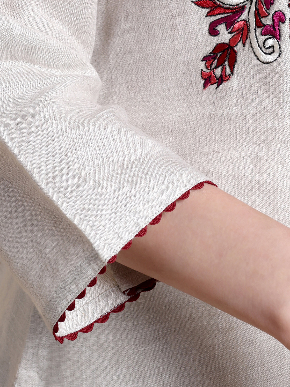 Close-up of a garment with red floral embroidery on a beige background