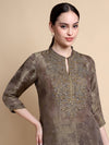 Woman wearing a brown embroidered kurta against a beige background