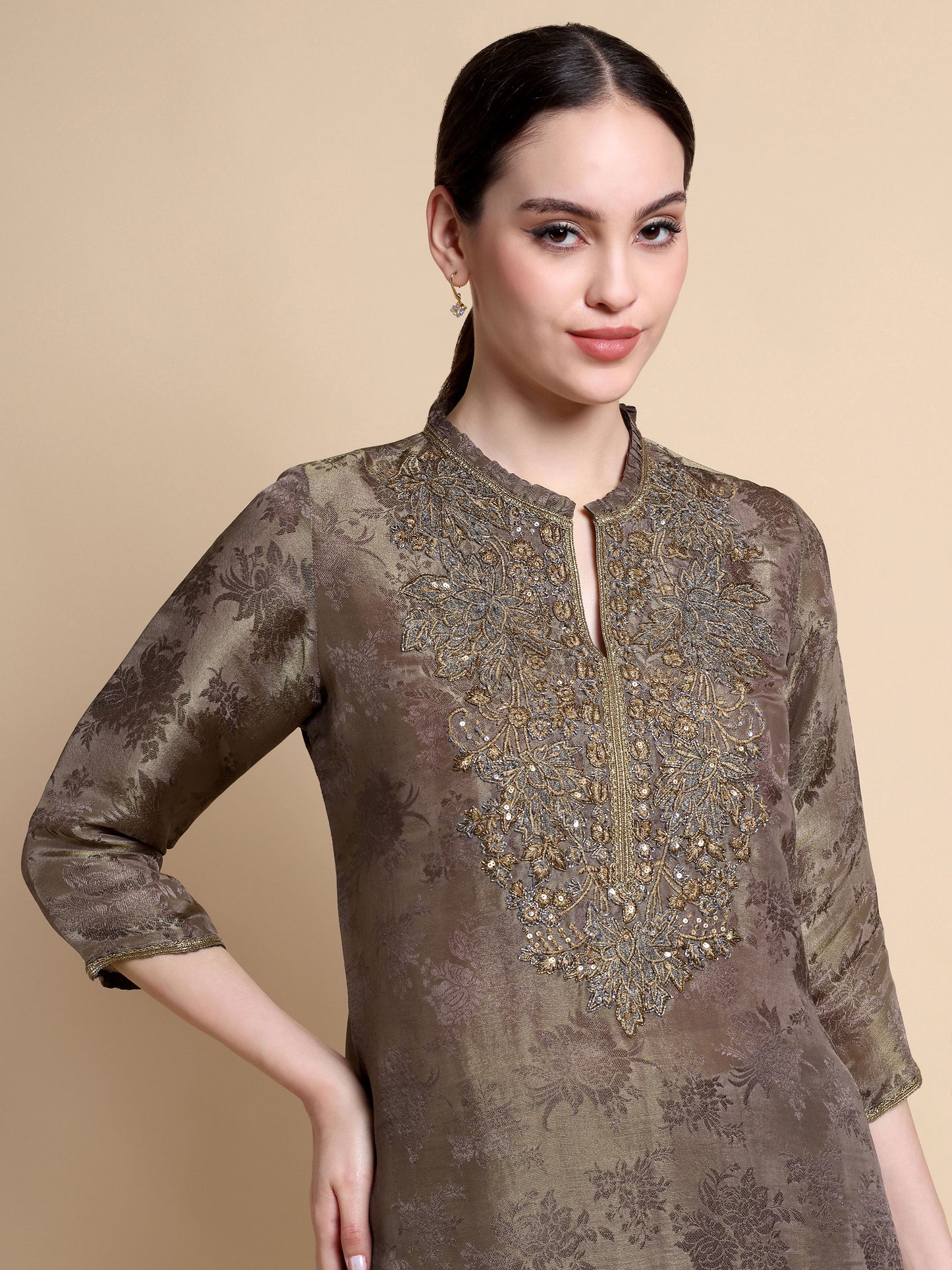 Woman wearing a brown embroidered kurta against a beige background