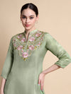 Woman wearing a light green kurta with floral embroidery on a beige background