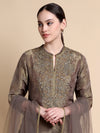 Woman wearing a brown embroidered outfit on a beige background