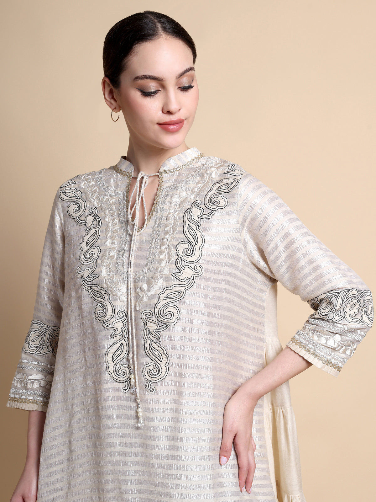 Woman wearing a cream-colored embroidered kurta against a beige background