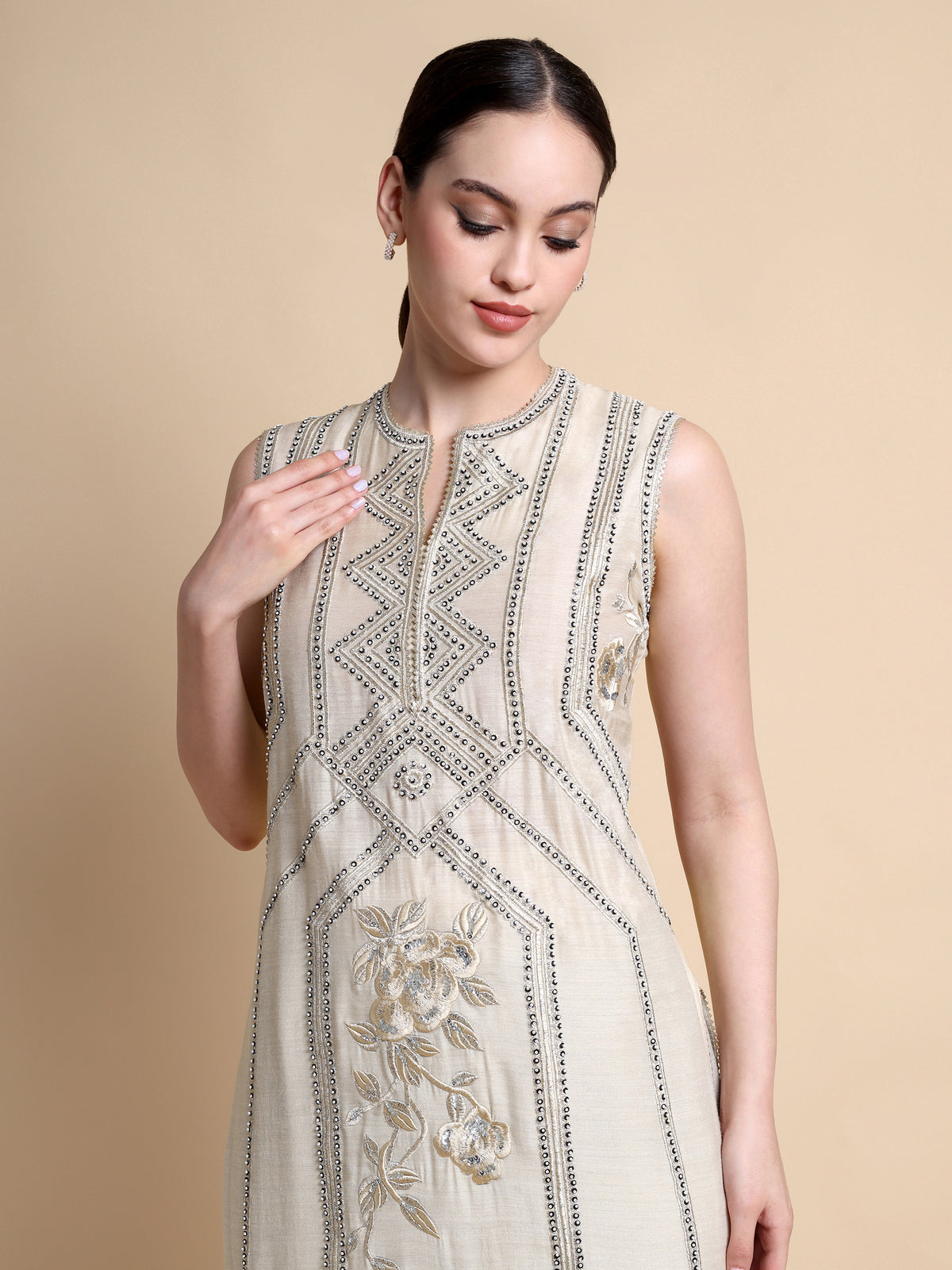 Woman wearing a beige embroidered dress against a beige background