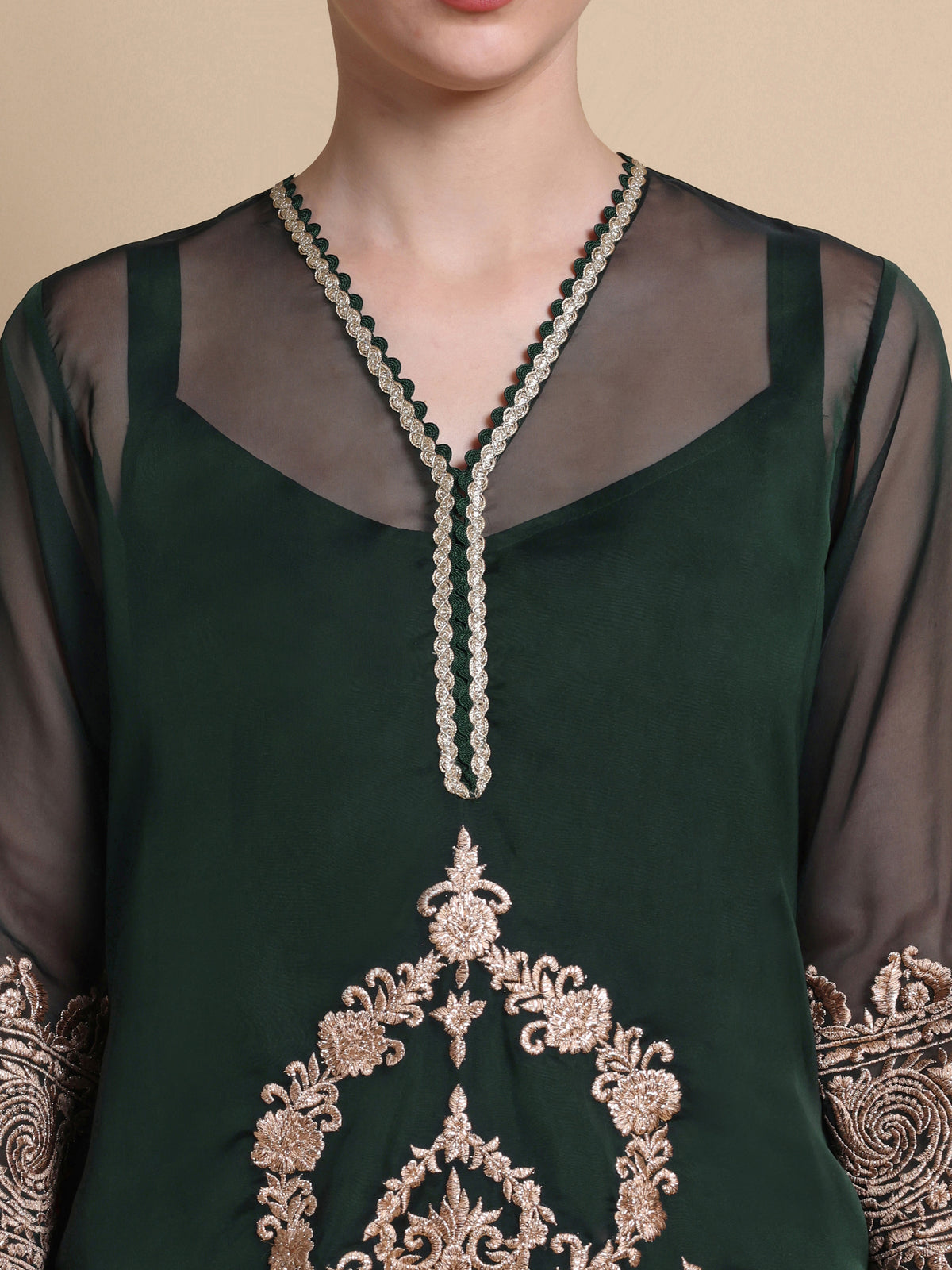 Green embroidered top with intricate patterns on a beige background