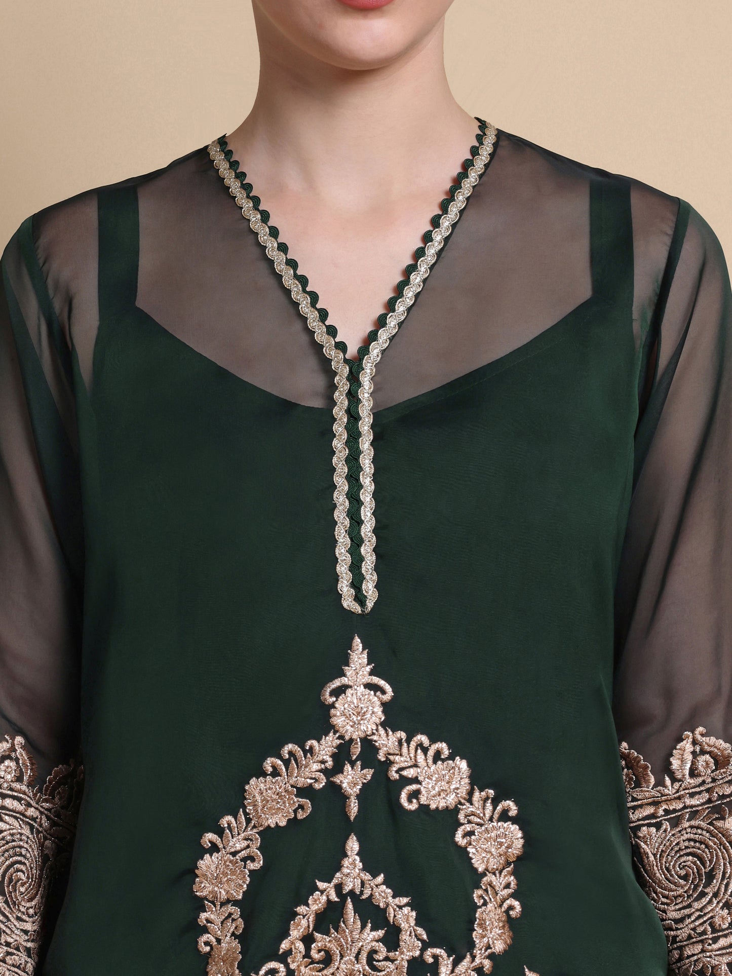 Green embroidered top with intricate patterns on a beige background